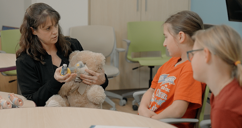 adult using teddy bear prop while speaking with two young girls