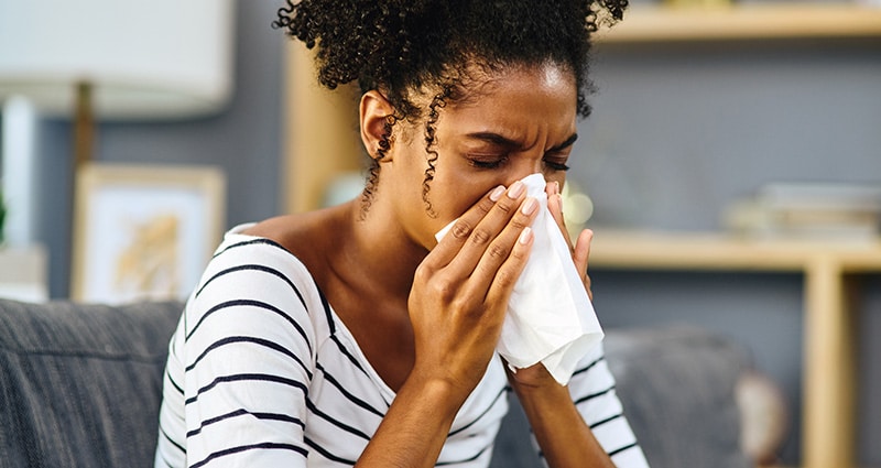 woman sneezing into tissue