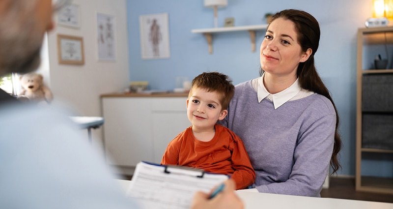 mom listening to medical provider with son in her lap