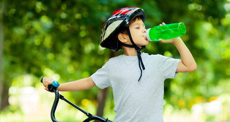 child in bicycle safety gear taking a drink of water