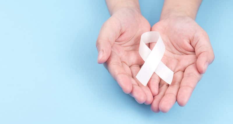 pair of hands holding a cancer ribbon