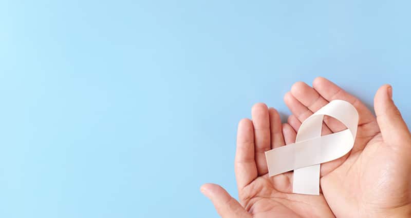 hands holding white ribbon on a light blue background