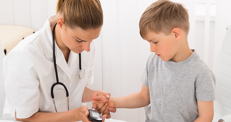 medical professional checking child's blood glucose