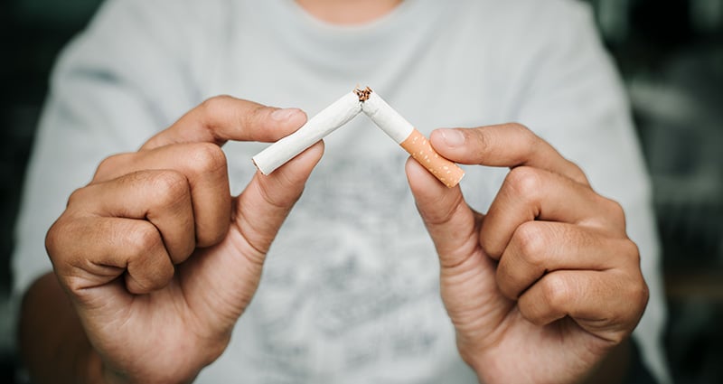 hands holding a broken cigarette