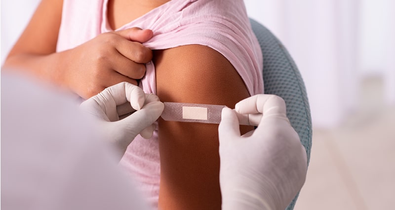 medical provider placing bandaid after vaccination