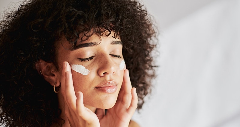 woman rubbing cream on her face