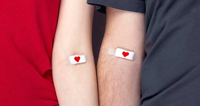 two arms with blood donation-implied bandages