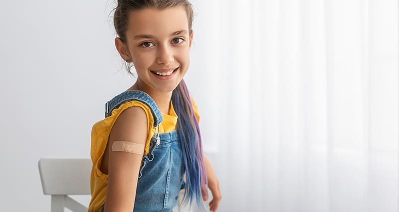 tween in overalls showing off her bandaid from vaccine