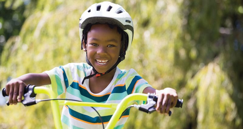happy child riding a bike in helmet