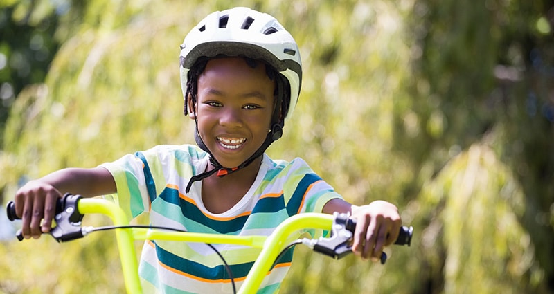 smiling kid riding bike wearing helmet