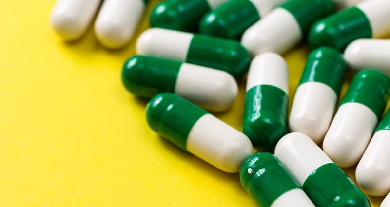 green and white capsules on yellow background