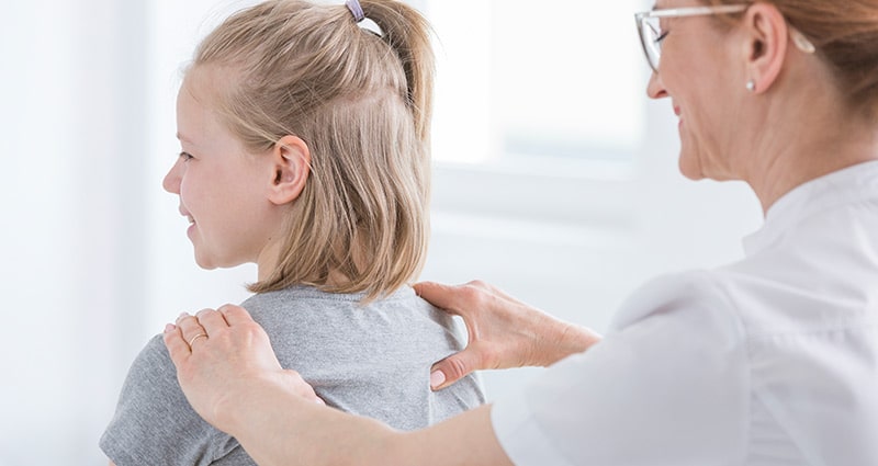 girl getting her back checked by medical professional