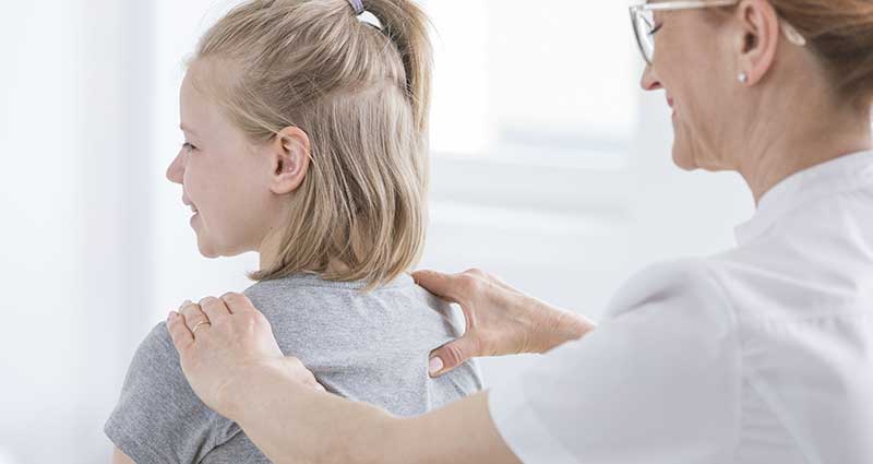 medical professional checking child's shoulders