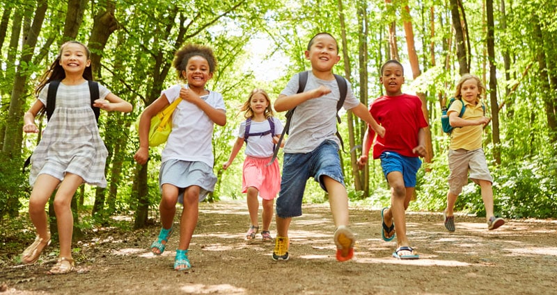 group of children running through a wooded trail