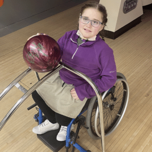 girl sitting in wheelchair with bowling ball