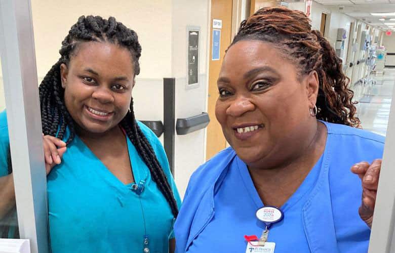 Smiling nurses stand in hospital hallway