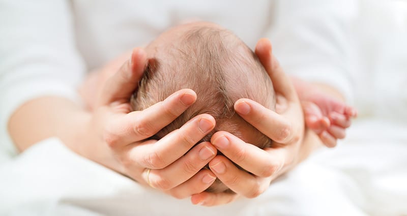 adult holding their baby's head in their hands