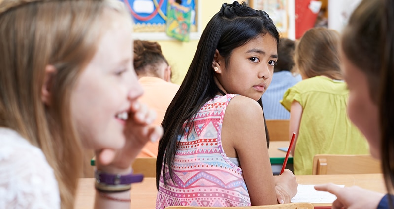 pensive girl in class while other girls whisper