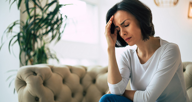 distressed looking woman sitting on couch