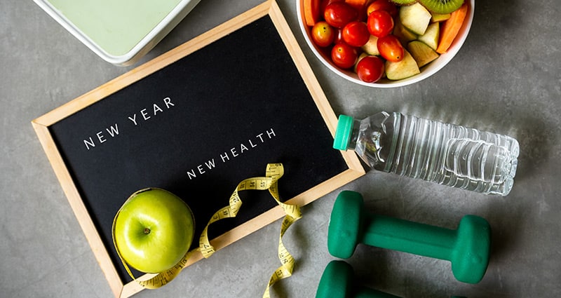 fruit, tape measure, weights and water with motivational letter board