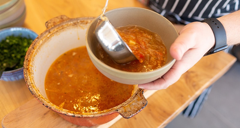 person dishing up bowl of soup