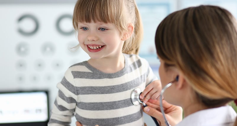 medical provider listening to girl's heart with stethoscope