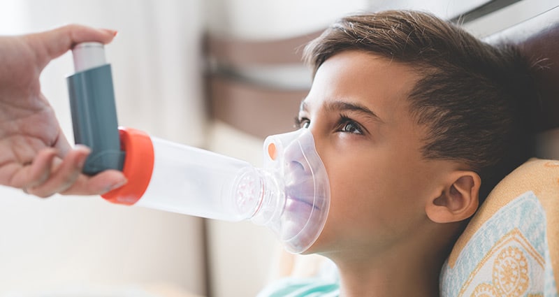 child using inhaler and spacer