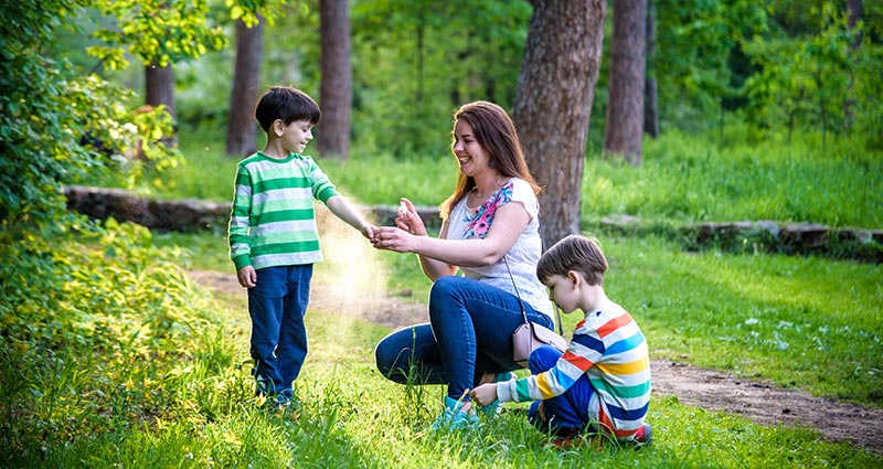 woman kneeling in woods with two children