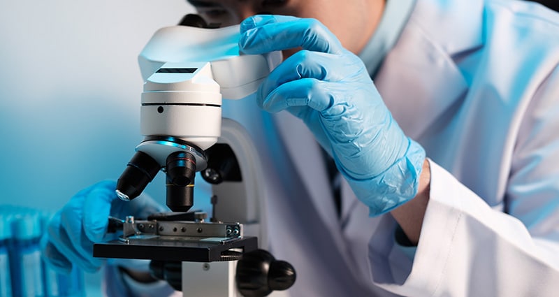 researcher looking at sample with microscope