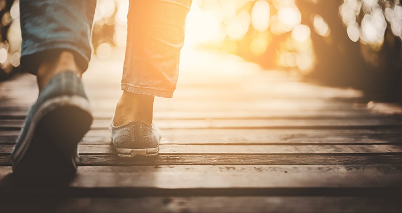 closeup of person's feet walking on bridge in golden sunlight