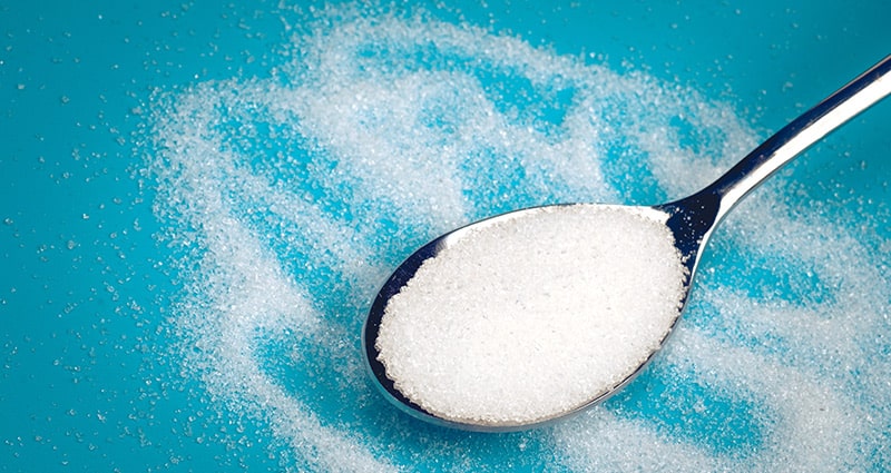 spoon of sugar on blue background