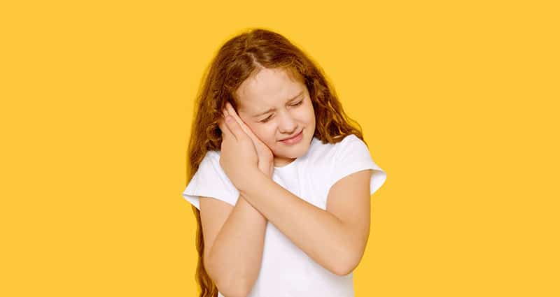 child holding her ear grimacing