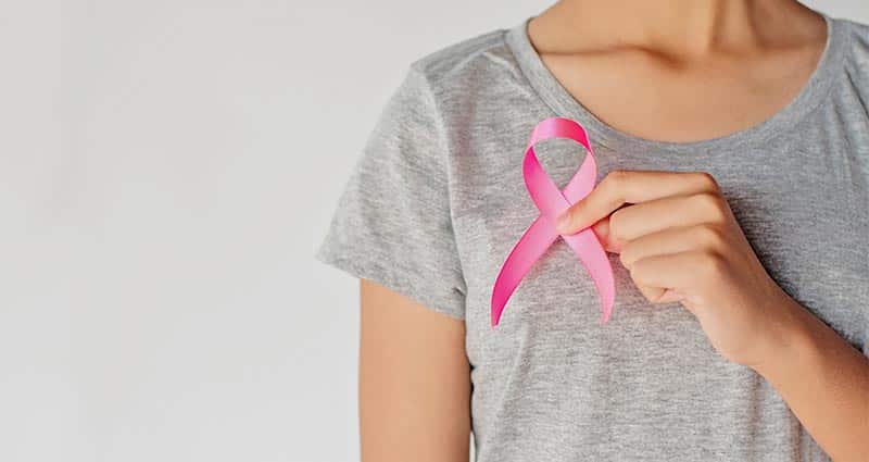 a woman holding a breast cancer ribbon