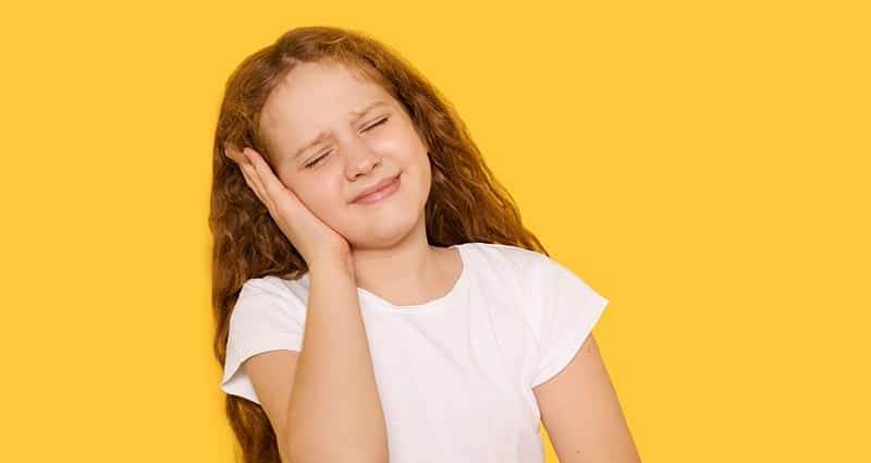 young girl holding her ear in distress