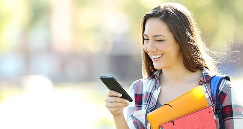 college student checking her phone and smiling