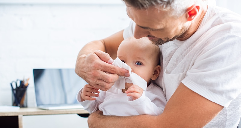 dad wiping infant's nose