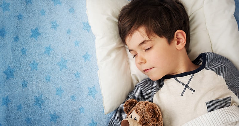 sleeping child holding teddy