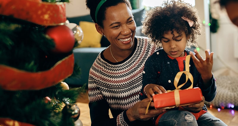 Child unwrapping gift sitting in parent's lap