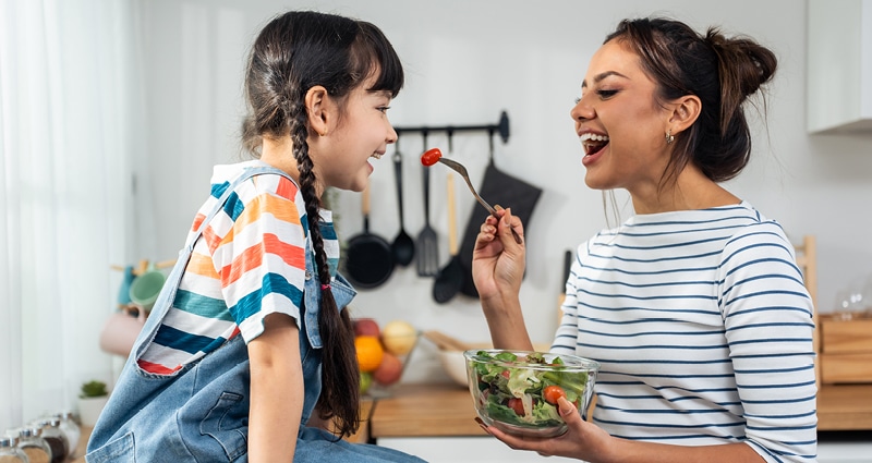 mom feeding daughter vegetables