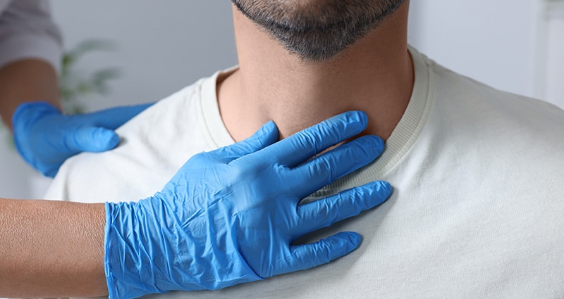 provider's gloved hand checking man's throat