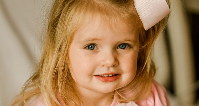 A girl toddler wearing a pink bow in her hair
