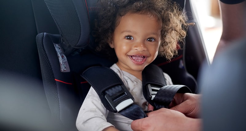 smiling child in carseat having straps adjusted
