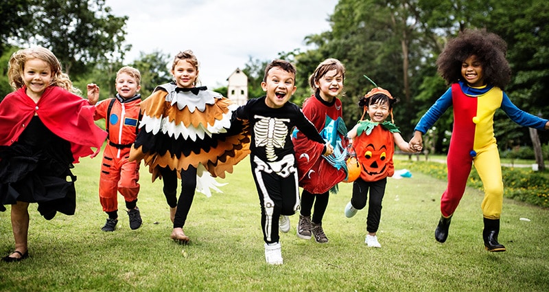 children in costumes running toward camera on green grass