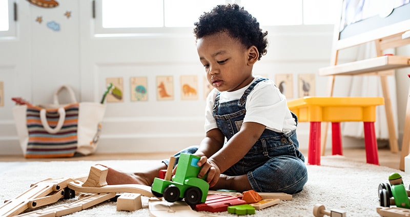 toddler playing with truck and train tracks