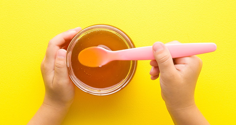 spoon in honey on yellow background
