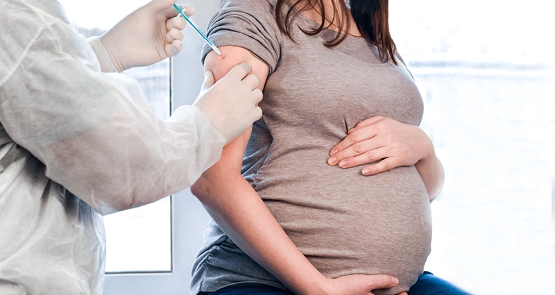 A healthcare provider administers a vaccine to a pregnant woman.