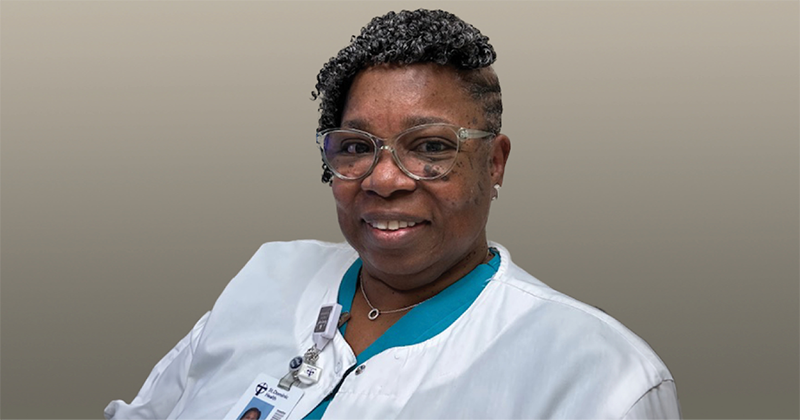 A woman wearing nurses clothes smiles at the camera